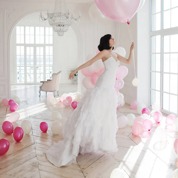 Mujer joven en vestido de novia en el interior de lujo vuela en globos rosados y blancos . —  Fotos de Stock