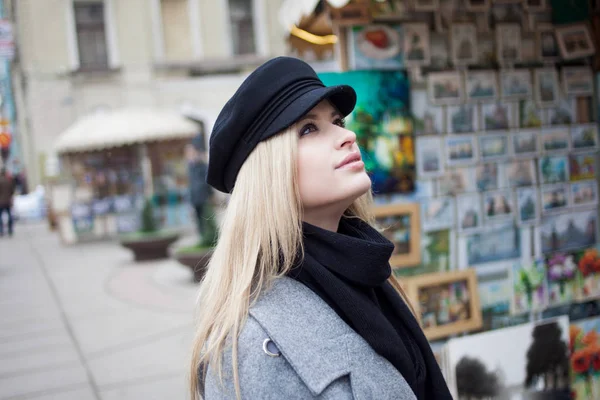 Joven, cadera y atractiva rubia paseando por la ciudad, chica con un sombrero elegante y un abrigo gris — Foto de Stock