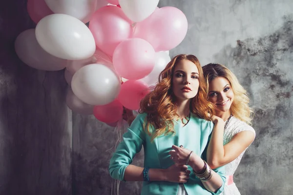 Blonde en roodharige. Twee jonge charmante vriendinnen op het feest. — Stockfoto