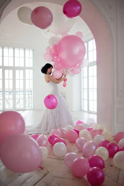 Mujer joven en vestido de novia en el interior de lujo con una masa de globos de color rosa y blanco . — Foto de Stock