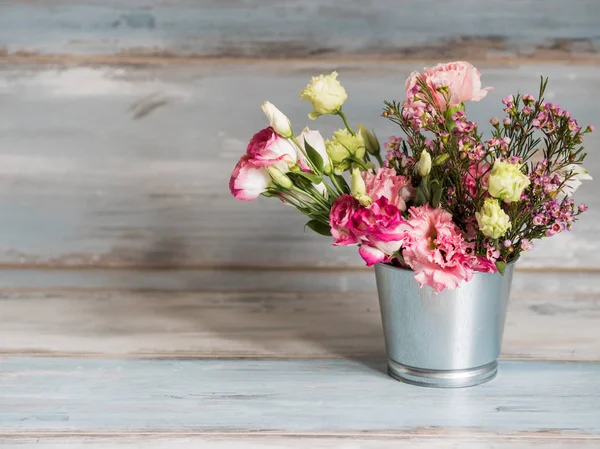 Jarní květy v malých plechovém kbelíku. Banda různých jarních květin v malé plechové vědro. Rustikální dřevěné pozadí. Volné místo vlevo — Stock fotografie