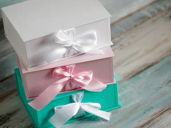 Trois coffrets cadeaux, blanc, rose et turquoise. Vue de dessus en diagonale sur un fond en bois. Cadeaux pour votre petite amie — Photo