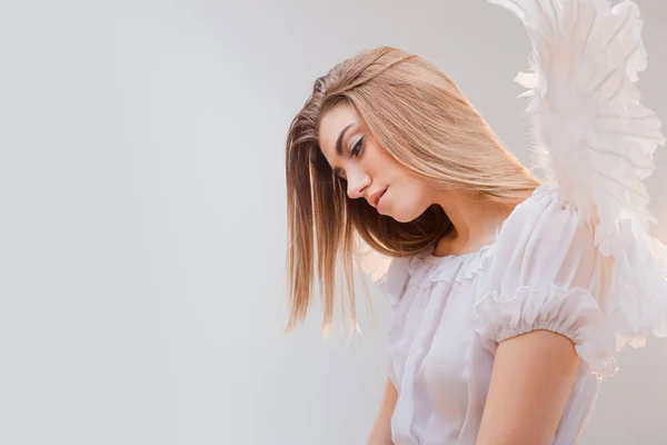 Een engel uit de hemel. Jonge, prachtige blonde meisje in de afbeelding van een engel met witte vleugels. — Stockfoto