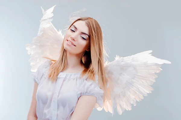 Um anjo do céu. Jovem, menina loira maravilhosa na imagem de um anjo com asas brancas . — Fotografia de Stock