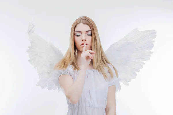 Άγγελος κρατά το μυστικό. Νέοι, υπέροχη ξανθιά κοπέλα στην εικόνα ενός αγγέλου με λευκά φτερά. — Φωτογραφία Αρχείου