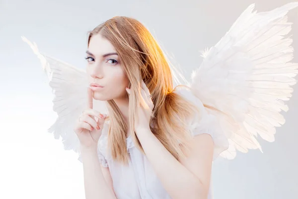 O Angel guarda o segredo. Jovem, menina loira maravilhosa na imagem de um anjo com asas brancas . — Fotografia de Stock