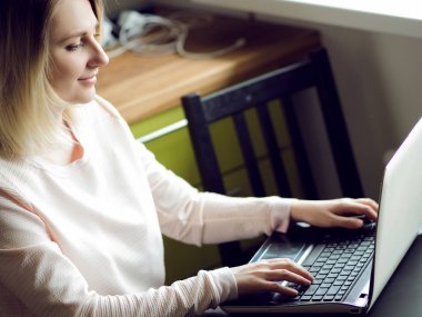 Sarışın genç kadın evde oturan bir dizüstü bilgisayar kullanarak. Internet çalışmalarında kavramı