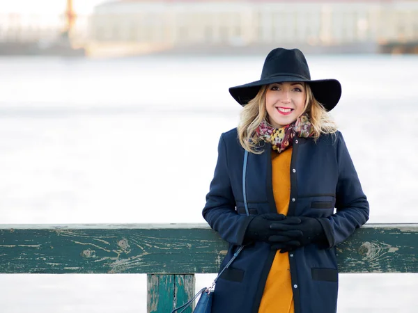 Mujer joven con sombrero y abrigo caminando. Retrato de la rubia en la calle, sonriente y divertida — Foto de Stock