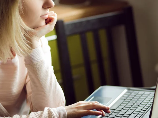 Une jeune femme blonde utilise un ordinateur portable, assise à la maison. Concept de travail sur Internet — Photo