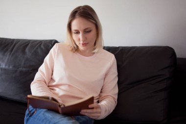 Genç kadın planlayıcısı ile. Portre evde kanepede iç. Planlama ve okuma