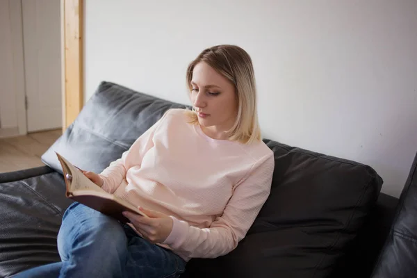 Молодая женщина с планировщиком. Портрет в интерьере, на диване дома. Планирование и чтение — стоковое фото