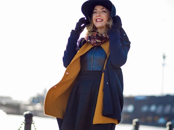 Frau mit elegantem Hut und Schal, zu Fuß. Porträt der charmanten Blondine auf der Straße. Starker Wind weht — Stockfoto