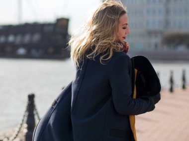 Yürüyen kadın şık şapka ve atkı. Sevimli sarışın sokakta portresi. Güçlü Rüzgar eser