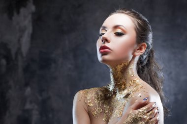 Güzel esmer kız altın folyo boyun ile yaratıcı görüntü ile. Stüdyo portre koyu arka plan arka plan üzerinde.