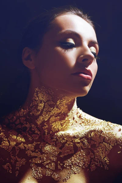 Hermosa chica morena con imagen creativa con lámina de oro en el cuello. Retrato de estudio sobre fondo oscuro . — Foto de Stock