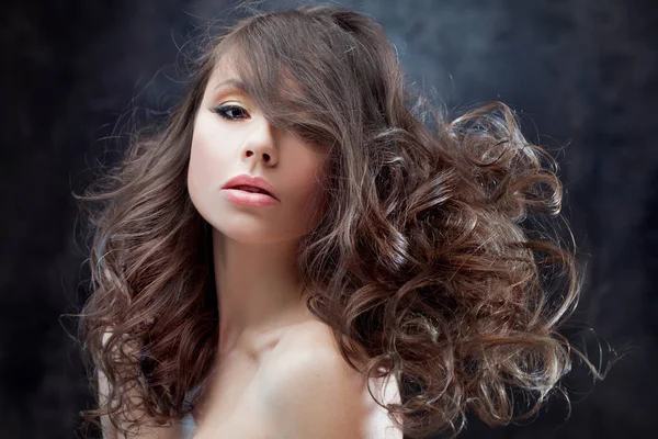 Όμορφη μελαχρινή κοπέλα με πολυτελές σγουρά μαλλιά. Πορτραίτο στούντιο σε ένα φόντο σκούρο φόντο. Εξαιρετική μαλλιά — Φωτογραφία Αρχείου