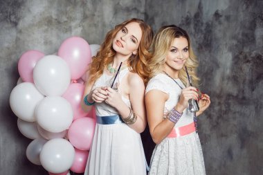 Sarışın ve Kızıl saçlı. İki genç kız arkadaşlar Balonlu partide büyüleyici. Gri dokulu arka plan üzerinde
