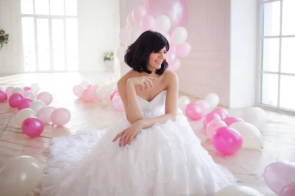 Mujer joven en vestido de novia en el interior de lujo con una masa de globos de color rosa y blanco . — Foto de Stock