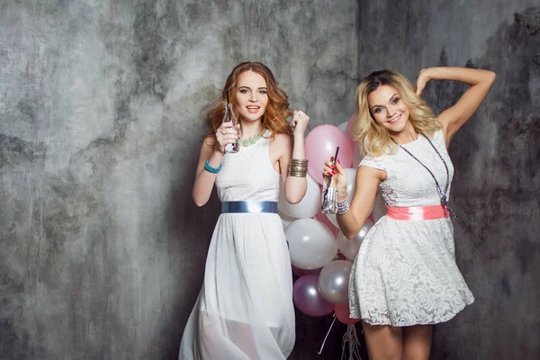 Loira e ruiva. Duas jovens namoradas encantadoras na festa com balões. Em fundo texturizado cinza — Fotografia de Stock