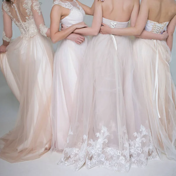 Four beautiful bridesmaid dresses in pastel colors are in each other\'s arms. Back, close-up lace skirts