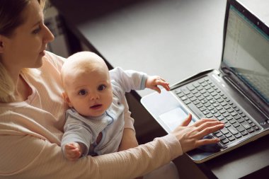 Genç güzel sarışın kadın, ev ofis bilgisayar ve bebeğini anne. İş ve çocuk bakımı.