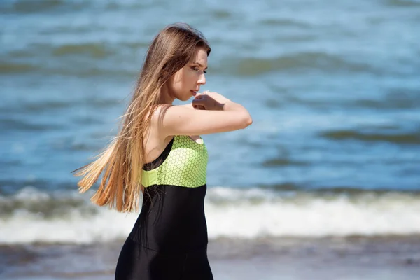 Piękna kobieta, nagrzewa się na plaży. Sportowiec joggingu podczas treningu na świeżym powietrzu, naprzeciwko oceanu — Zdjęcie stockowe