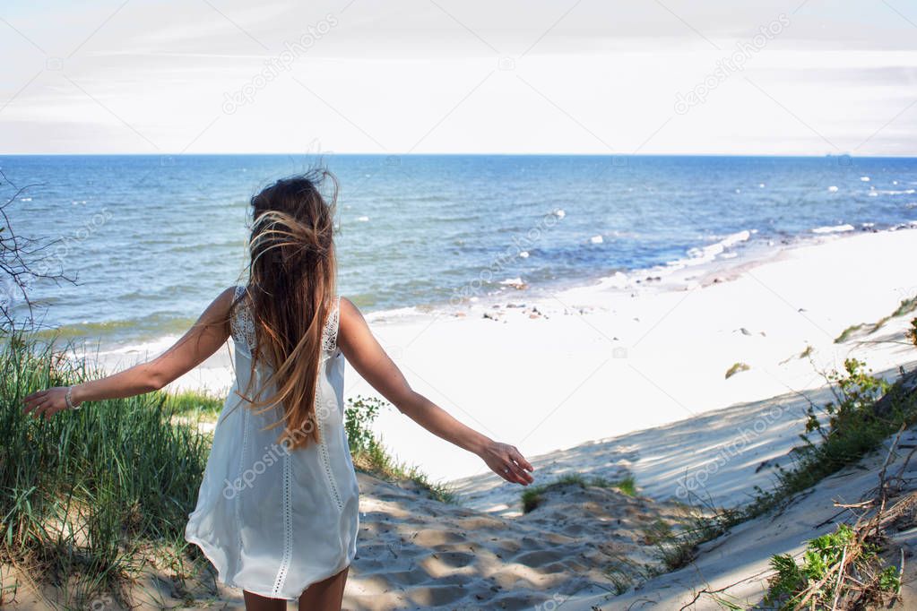 Young cheerful girl on the seashore. Open arms embracing nature, summer sea landscape