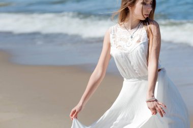 Deniz kıyısında genç sevimli esmer kadın. Beyaz yazlık elbise güzel kız. Dalgalar deniz arka plan üzerinde