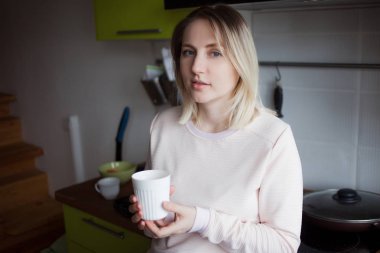 Genç sarışın kadın evde. Çay, portre mutfakta tutan kız