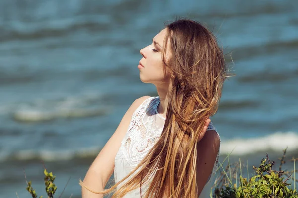 Jonge charmante brunette vrouw op Zeekust. Geweldig uitzicht vanaf de top. Portret van de jonge vrouw tegen heldere hemel — Stockfoto