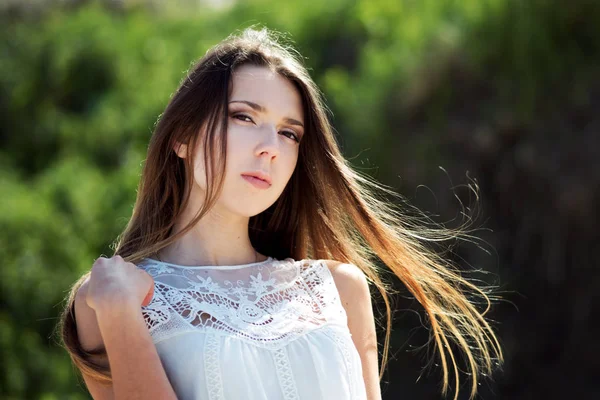 Giovane donna bruna affascinante. Ritratto di primo piano all'aperto su uno sfondo di fogliame verde . — Foto Stock