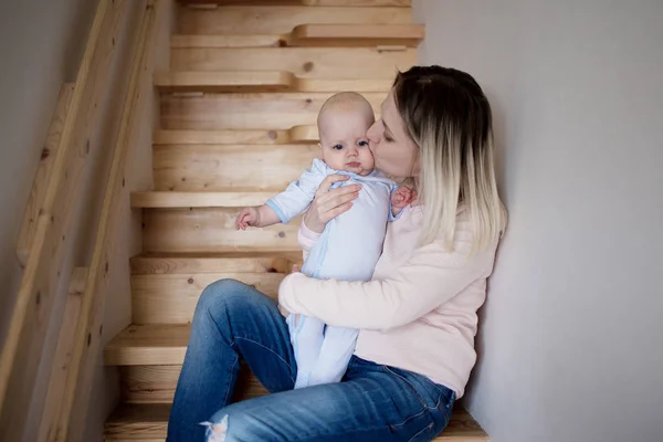 젊은 어머니는 계단에 앉아 아이 함께 집. 뺨에 키스 하는 그녀의 아들 — 스톡 사진