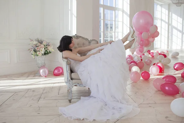 Jonge vrouw in trouwjurk in luxe interieur met een massa van roze en witte ballonnen. — Stockfoto
