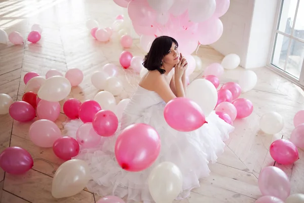 Mujer joven en vestido de novia en el interior de lujo con una masa de globos de color rosa y blanco . — Foto de Stock