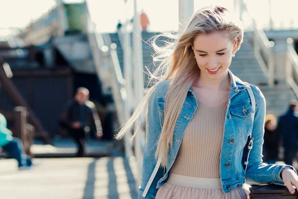Vrolijk meisje aan de kust. Jonge blonde vrouw die lacht. Trendy stijl — Stockfoto
