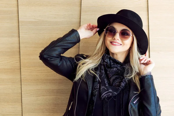 Funny and beautiful blonde in sun glasses and a hat. Trendy girl portrait outdoor. Laughs and holds hat. Toned picture — Stock Photo, Image