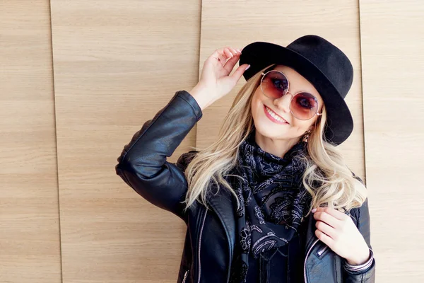 Drôle et belle blonde dans des lunettes de soleil et un chapeau. Portrait fille à la mode en plein air. Rires et tient le chapeau — Photo