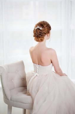 Güzel kızıl saçlı gelin görünümü şık saç modeli, geri sandalyede oturur. Lüks gelinlik genç kadın