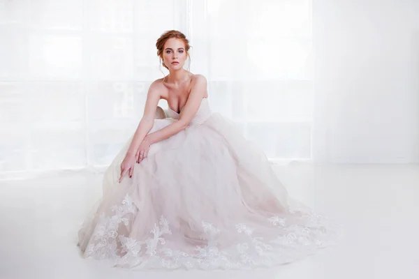 Portret van een mooi meisje in een trouwjurk. Bruid in luxe jurk zittend op een stoel — Stockfoto