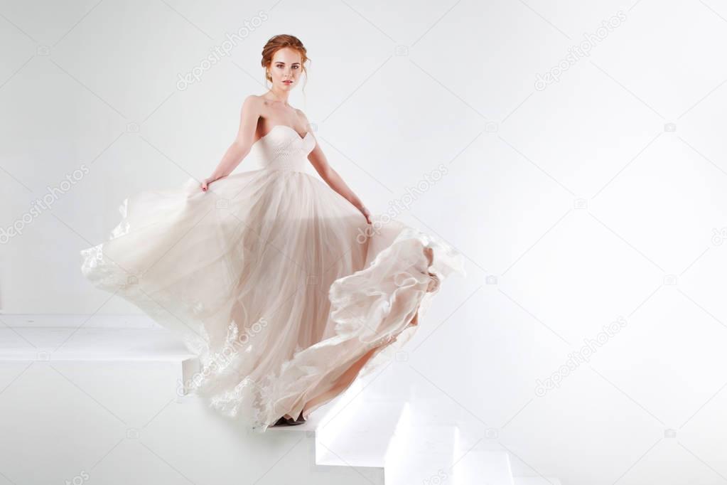 Portrait of a beautiful girl in a wedding dress. Bride in luxurious dress dancing and swinging hem skirt