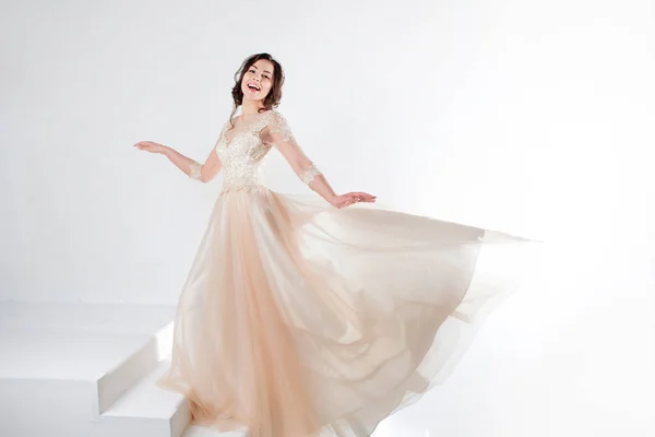 Retrato de una hermosa chica en un vestido de novia. Novia en vestido de lujo bailando y balanceo dobladillo falda — Foto de Stock