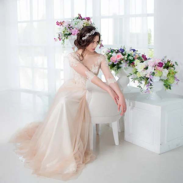 Portret van een mooi meisje in een trouwjurk. Bruid in een luxe jurk, in een mooie witte interieur — Stockfoto