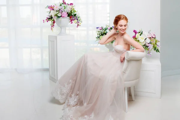 Portrait of a beautiful girl in a wedding dress. Bride in luxurious dress sitting on a chair — Stock Photo, Image