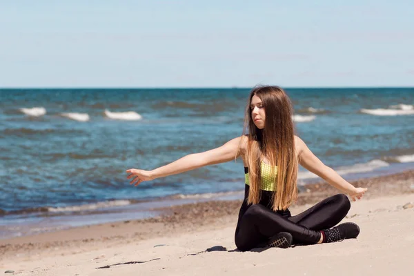 Vacker kvinna värmer upp på stranden. Flicka idrottaren vila efter träning vid havet — Stockfoto