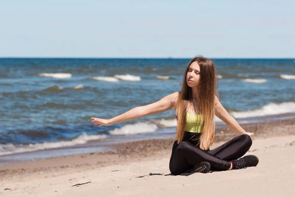 Piękna kobieta, nagrzewa się na plaży. Sportowiec dziewczynka odpoczynku po treningu nad brzegiem morza — Zdjęcie stockowe