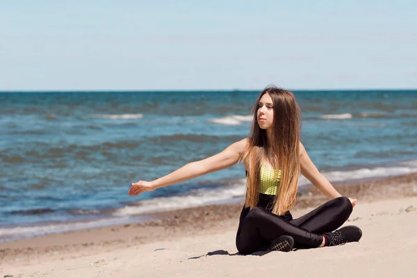 Красивая женщина греется на пляже. Девушка спортсменка отдыхает после тренировки на набережной — стоковое фото