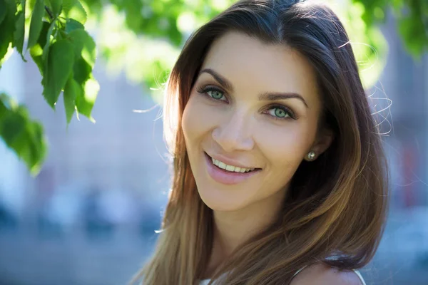 Retrato de cerca de una hermosa mujer, morena. Sobre el fondo la naturaleza veraniega —  Fotos de Stock