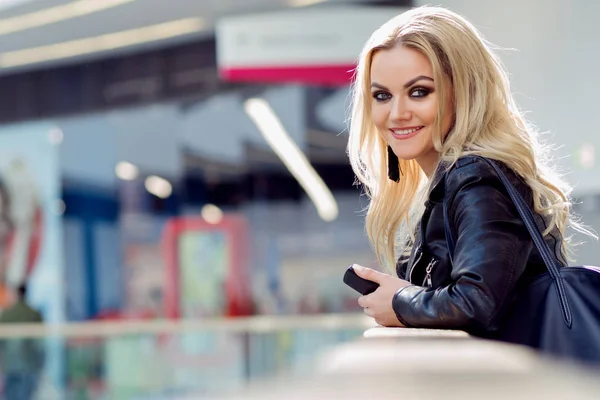 Portret van een mooie jonge blonde met het oog make-up. Lachende vrouw met mobiele telefoon — Stockfoto