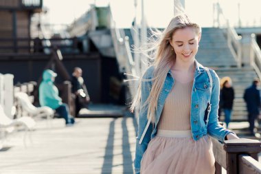Deniz kıyısı genç neşeli kız. Sarışın genç kadın gülümsüyor. Son moda stil
