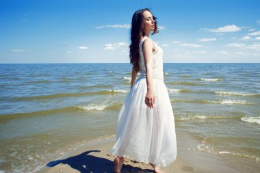 Deniz kıyısı üzerinde beyaz elbiseli genç güzel esmer kadın